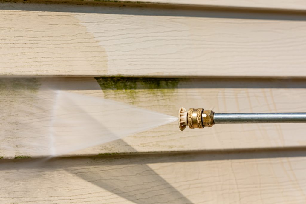 cleaning siding on home with pressure washing