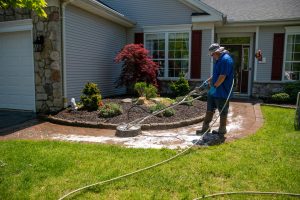 man using a circular power washer to clean a brick walkway in front of a house